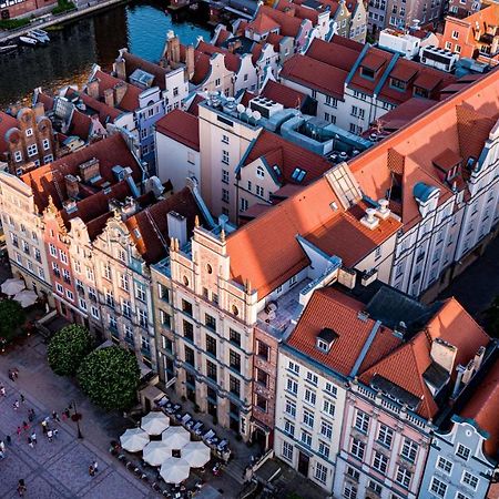 Radisson Blu Hotel, กดัญสก์ ภายนอก รูปภาพ The photo shows a bird's-eye view of a picturesque urban area, likely in a historical city. It features a cluster of buildings with a mix of architectural styles, characterized by colorful facades and predominantly red rooftops. The buildings seem to