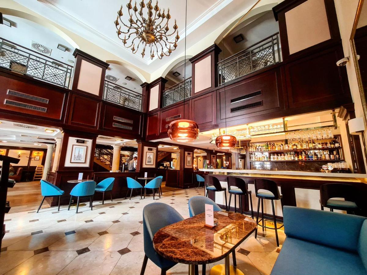 Radisson Blu Hotel, กดัญสก์ ภายนอก รูปภาพ The photo depicts an elegant interior of a bar or restaurant. It features a high ceiling with a decorative chandelier and wooden paneling, creating a sophisticated atmosphere. The space is well-lit, with a long bar counter visible in the background, 