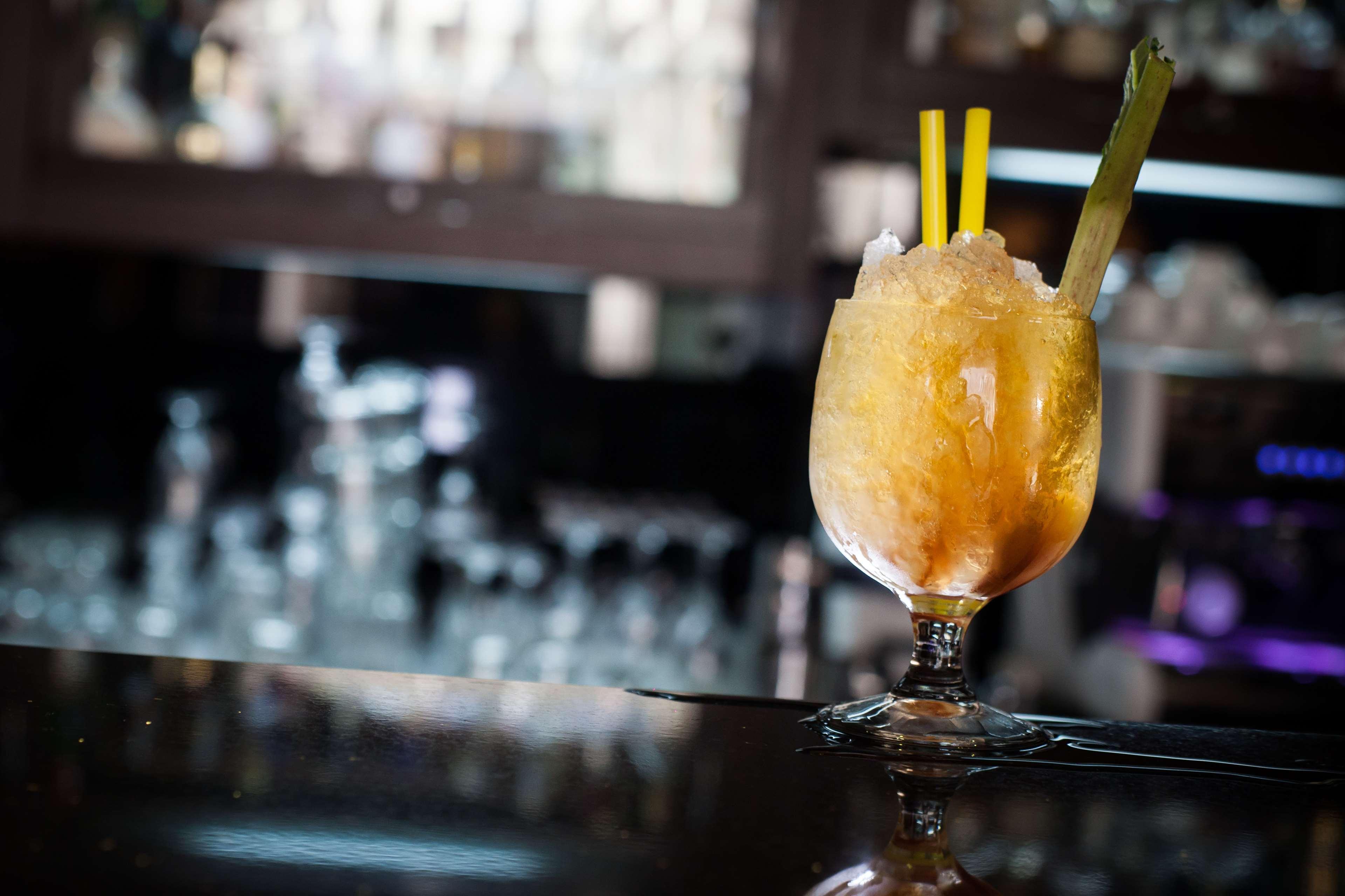 Radisson Blu Hotel, กดัญสก์ ภายนอก รูปภาพ The photo shows a cocktail served in a decorative glass. The drink appears to be slushy or frozen, with a yellow-orange hue and topped with crushed ice. It has two yellow straws and a piece of celery as garnish. The setting suggests it is in a bar or