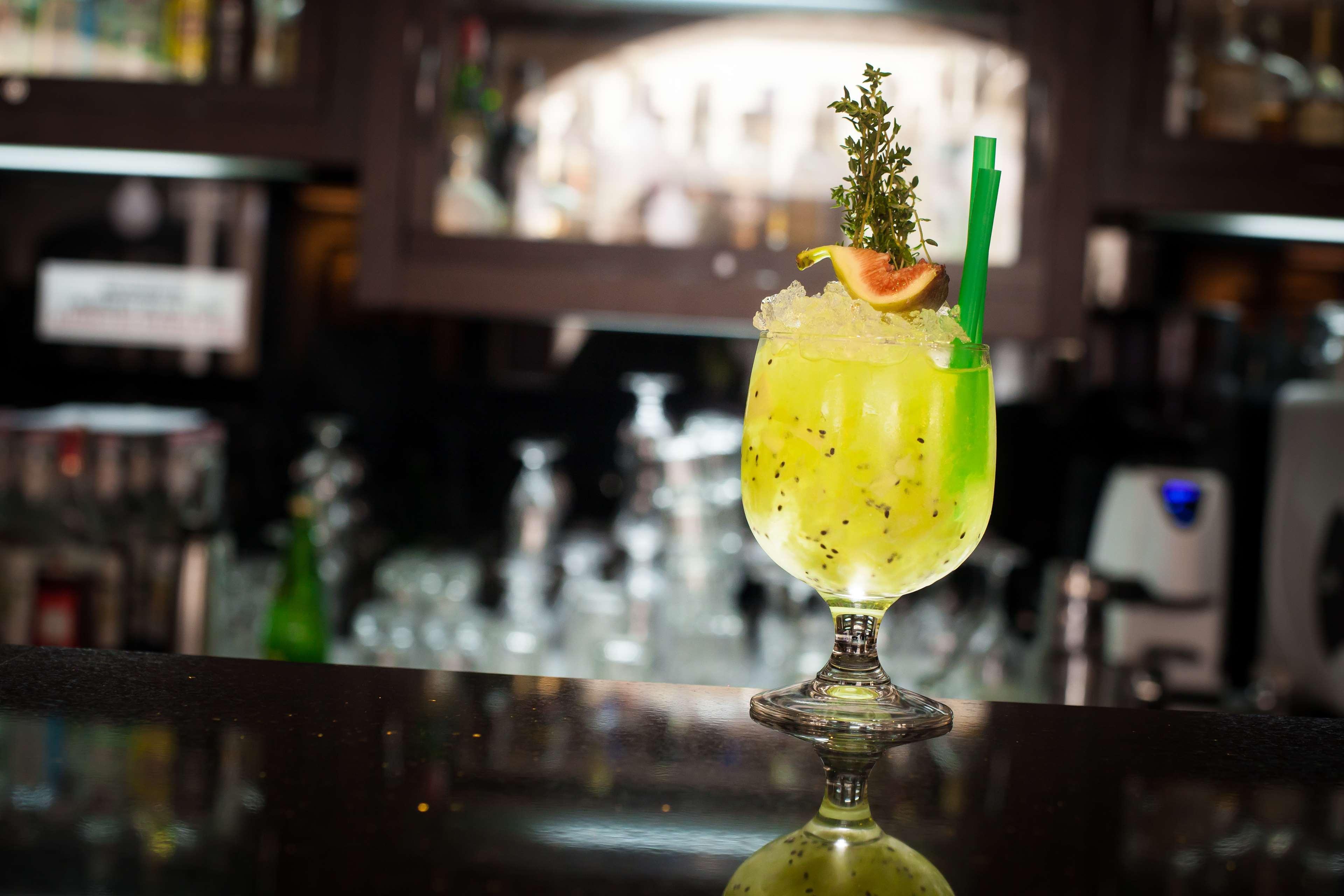 Radisson Blu Hotel, กดัญสก์ ภายนอก รูปภาพ The photo shows a vibrant, green cocktail served in a stylish glass with a wide base and an elegant stem. The drink is garnished with a slice of fruit and a sprig of herbs, adding visual appeal. A green straw is inserted into the drink, and it appear