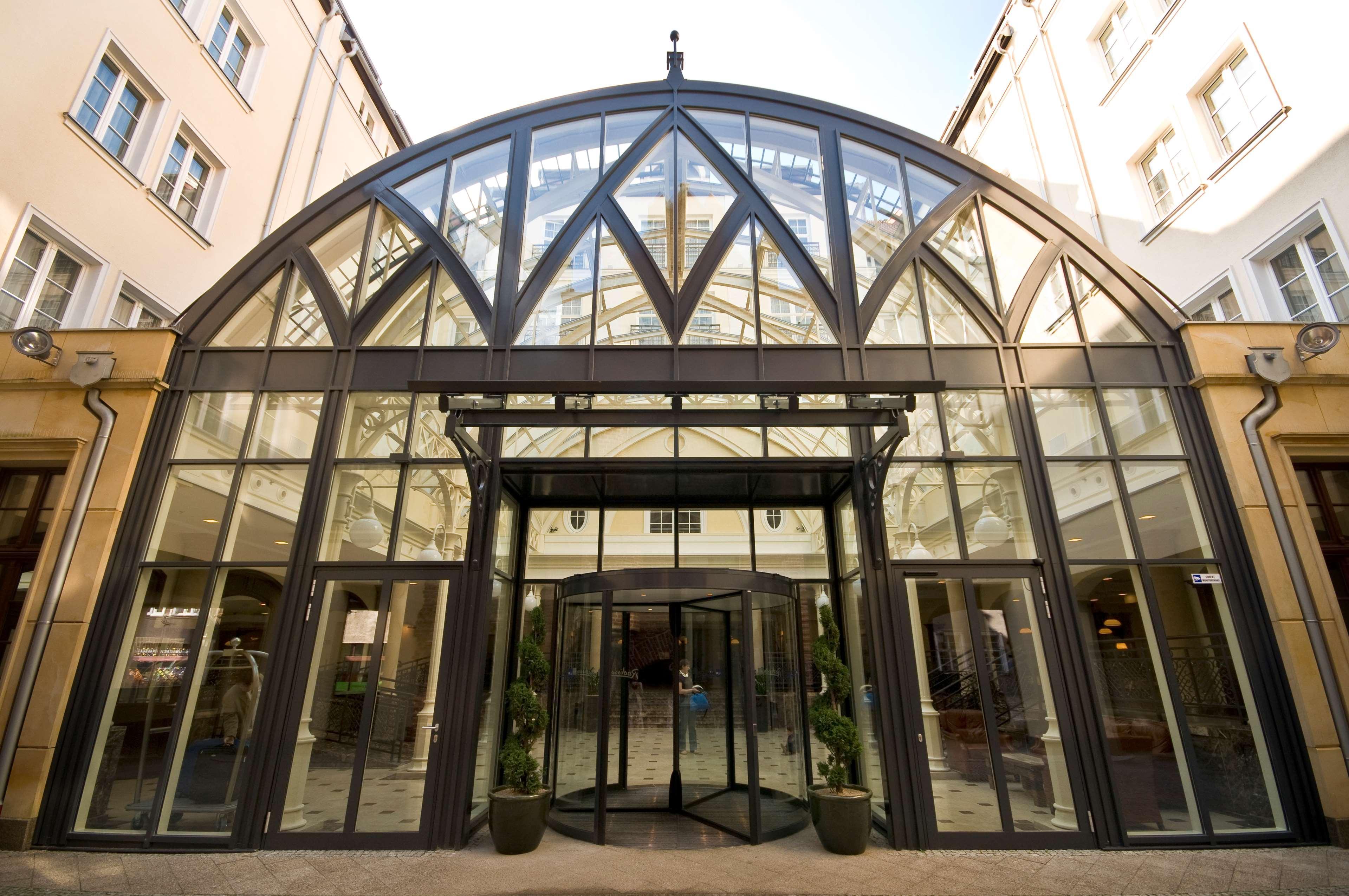 Radisson Blu Hotel, กดัญสก์ ภายนอก รูปภาพ The photo shows a modern glass entrance, featuring a large, arched roof structure. The facade is predominantly made of glass and metal, allowing natural light to illuminate the interior. There are revolving doors at the center, flanked by symmetrical
