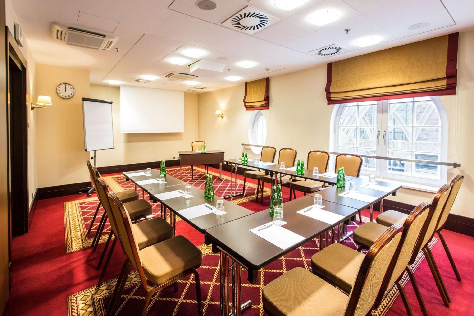 Radisson Blu Hotel, กดัญสก์ ภายนอก รูปภาพ The photo shows a conference room set up for a meeting. It features a large rectangular table surrounded by several chairs. On the table, there are bottles of water and paper notepads for participants. A flip chart is positioned at one side of the ro