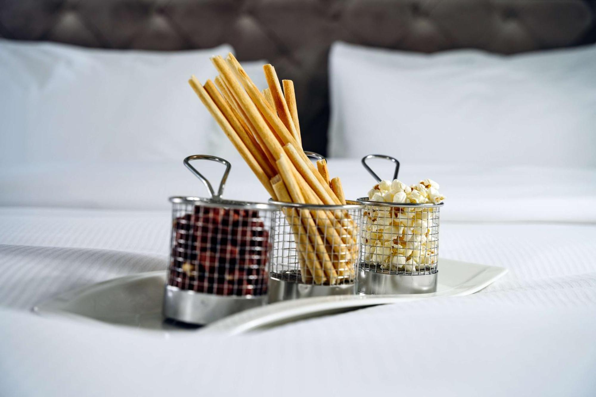 Radisson Blu Hotel, กดัญสก์ ภายนอก รูปภาพ The photo shows a tray with three small metal baskets. Each basket contains a different type of snack. 

1. The first basket holds breadsticks, which are long and thin, arranged upright.
2. The second basket contains what appears to be chocolate-cove