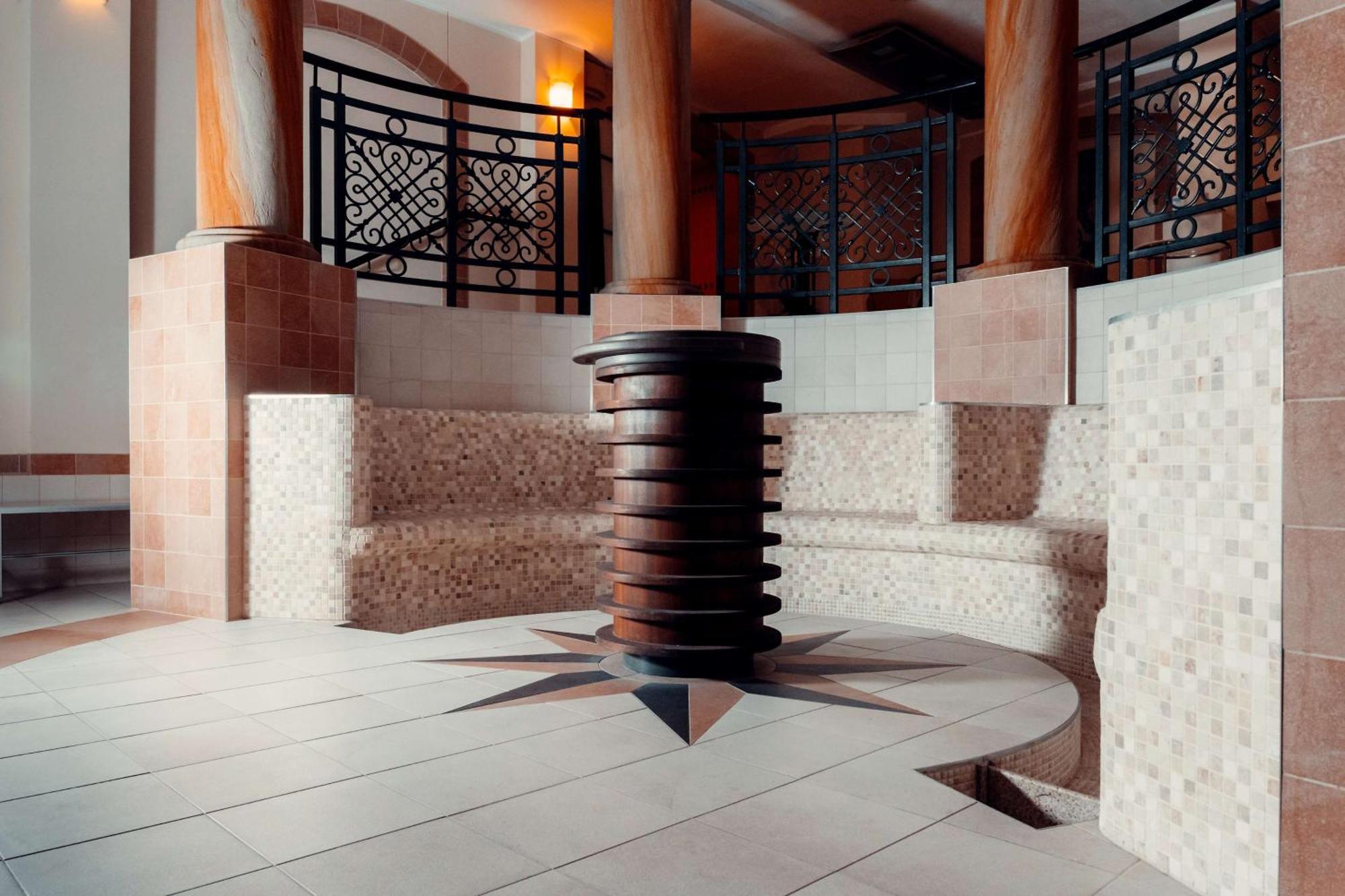 Radisson Blu Hotel, กดัญสก์ ภายนอก รูปภาพ The photo showcases a well-designed interior space, likely part of a spa or wellness center. In the center, there is a circular seating area made of tiled blocks arranged in a semicircular pattern. The floor features a star-shaped design with contras