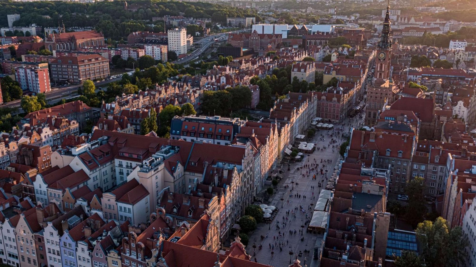 Radisson Blu Hotel, กดัญสก์ ภายนอก รูปภาพ The photo depicts a scenic aerial view of a city, likely Gdańsk in Poland. The landscape features historical buildings with distinctive architecture, characterized by colorful facades and prominent rooftop designs. A bustling street runs through the 
