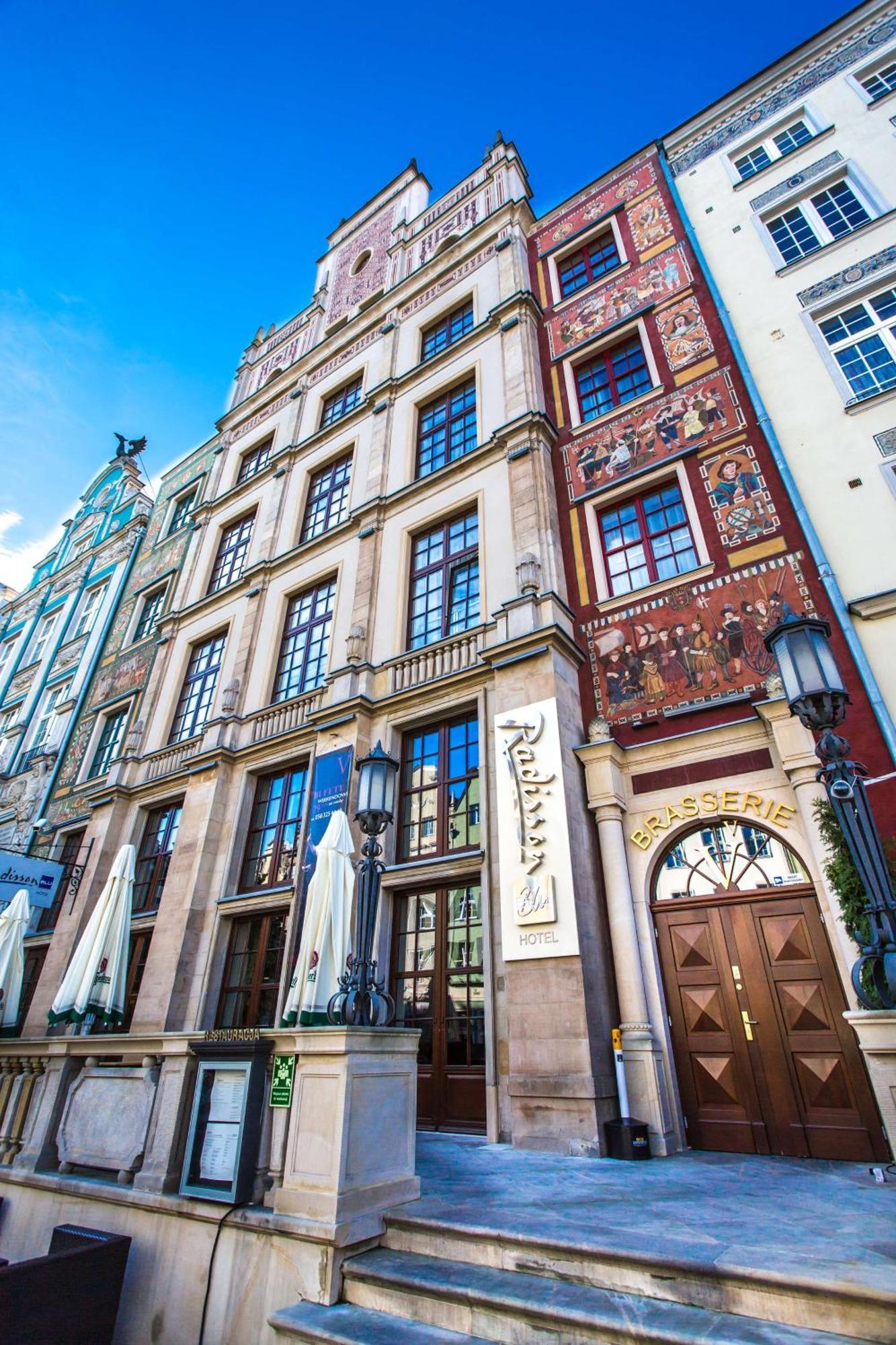 Radisson Blu Hotel, กดัญสก์ ภายนอก รูปภาพ The photo shows a historic building with a richly decorated facade. The architecture features large windows and intricate details, including murals or painted scenes on the walls. There is a sign that indicates a brasserie, suggesting that this locat