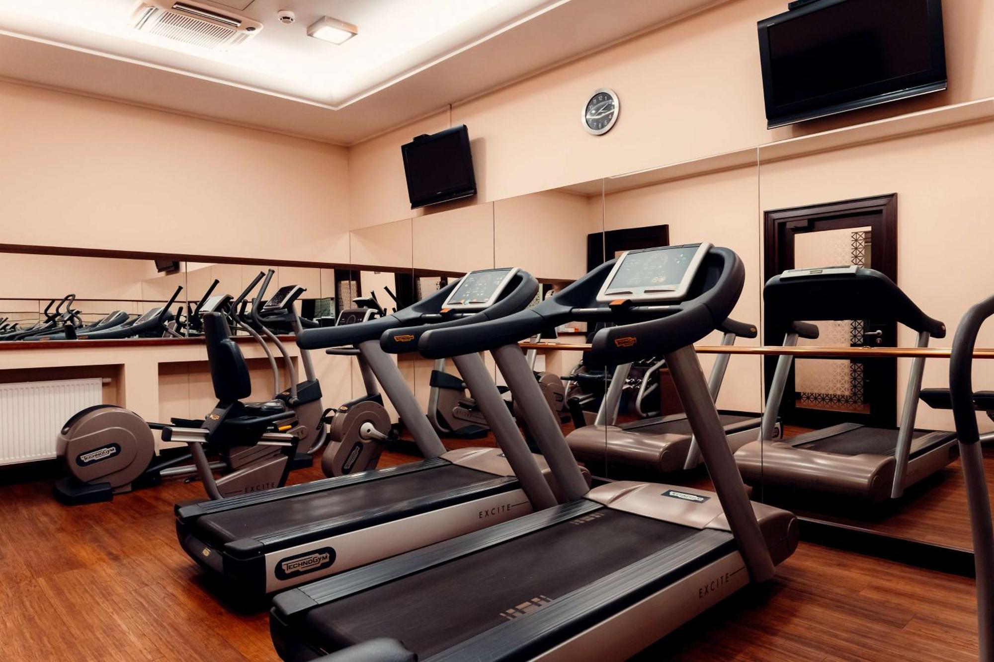 Radisson Blu Hotel, กดัญสก์ ภายนอก รูปภาพ The photo shows a gym or fitness center with several exercise machines. There are multiple treadmills lined up in the foreground, each equipped with a display screen. In the background, there are additional fitness machines, including stationary bike
