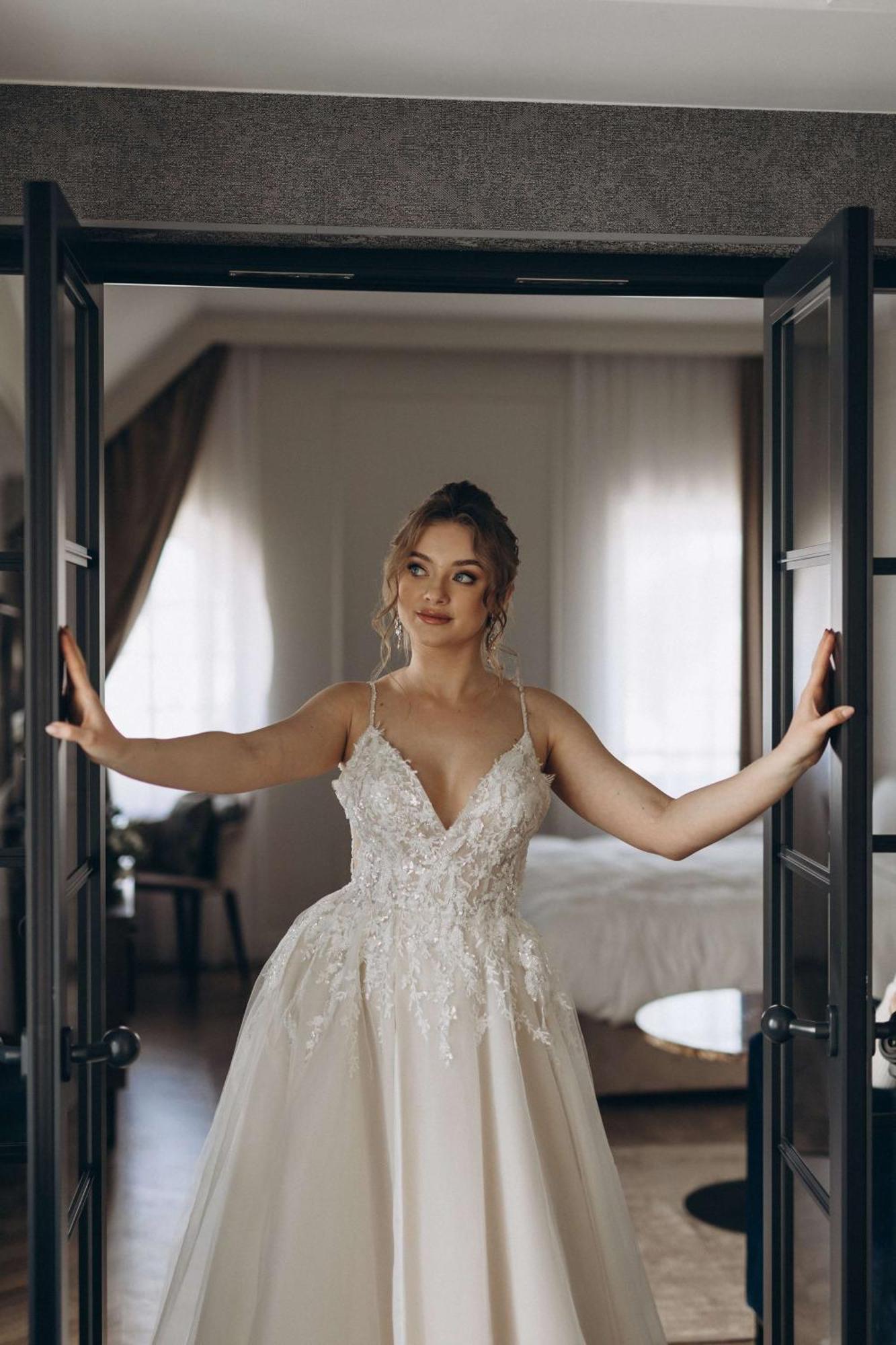Radisson Blu Hotel, กดัญสก์ ภายนอก รูปภาพ The photo shows a young woman standing between two open doors. She is wearing a beautiful wedding gown adorned with intricate details. Her hair is styled elegantly, and she has a thoughtful expression on her face. The setting appears to be a stylish 